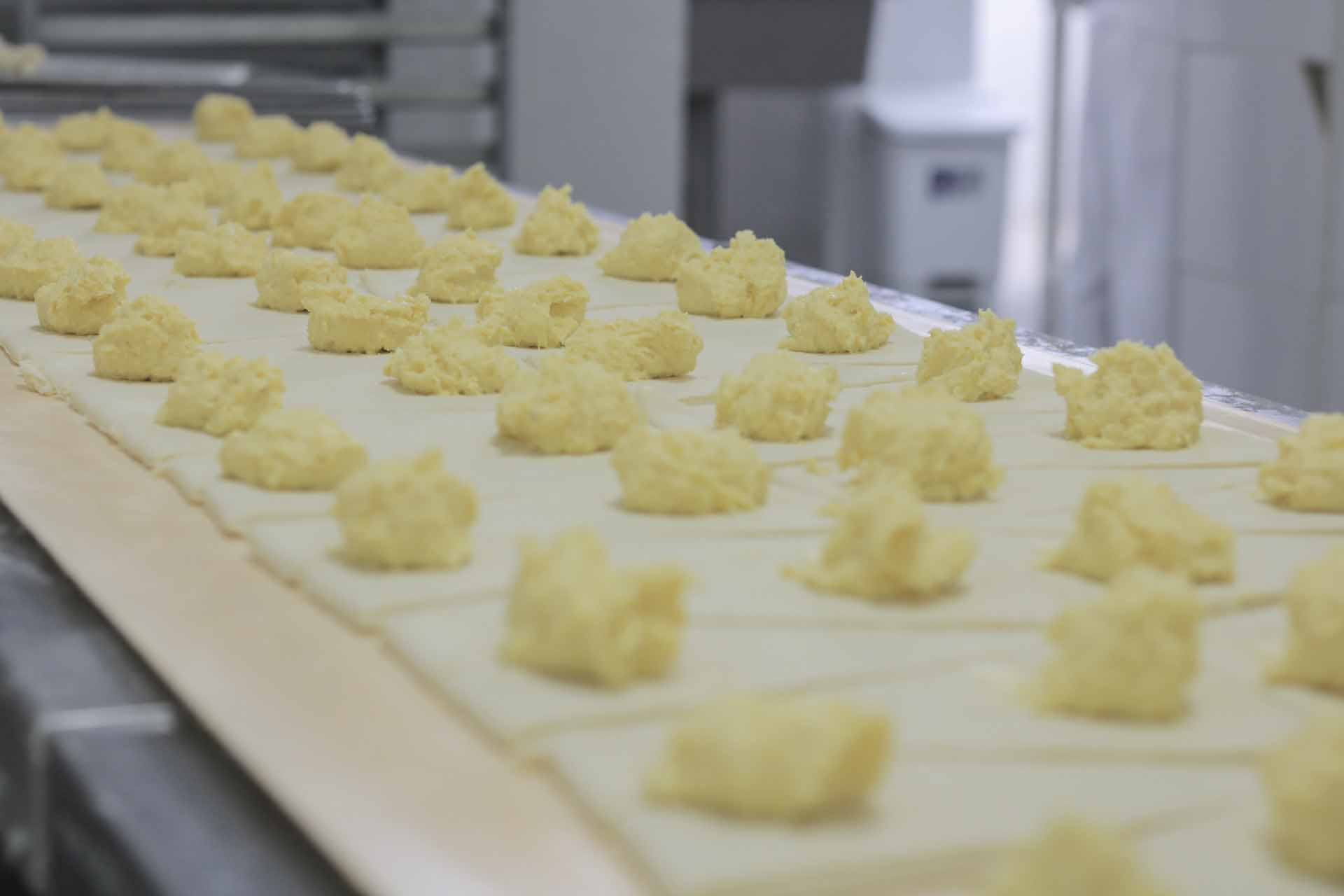 Linha de produção da Ké Lanche: recheio sendo porcionado sobre a massa aberta, antes do fechamento